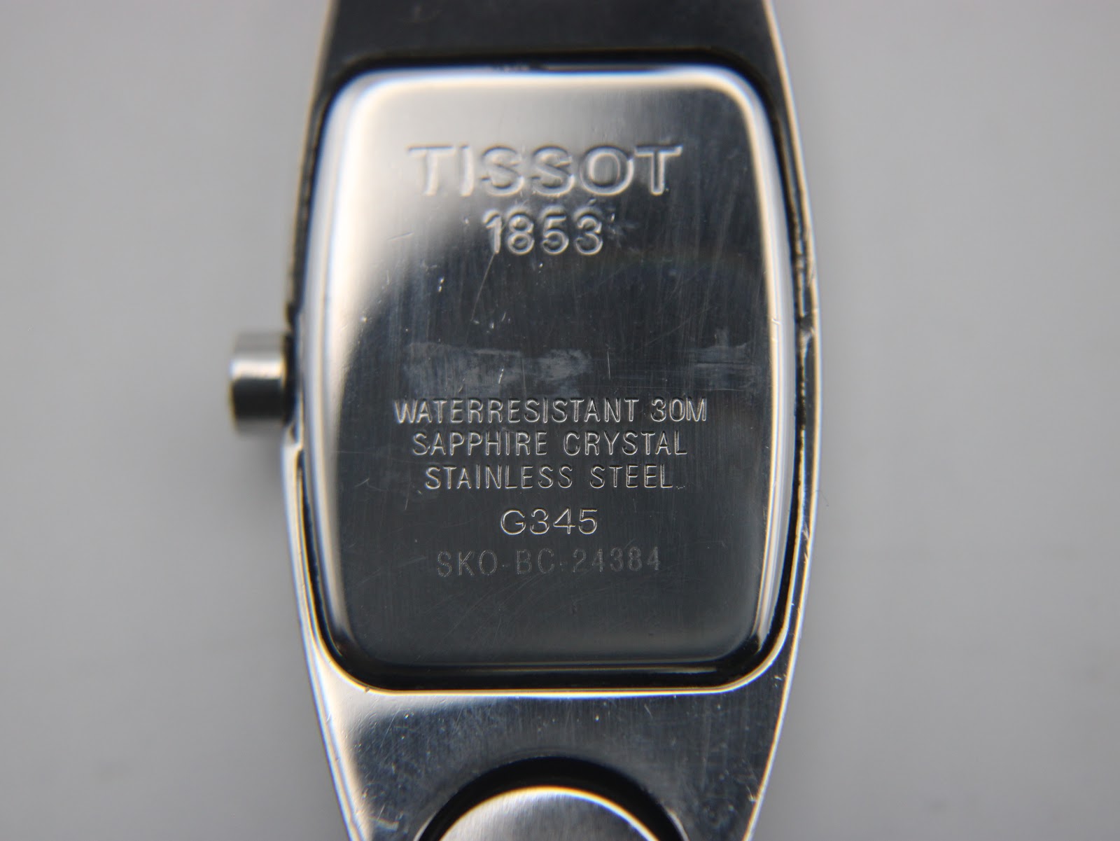 Close-up of the Tissot G345 case back, showing engravings for Tissot, 1853, water resistance, sapphire crystal, stainless steel, model G345, and serial SKO-BC-24384.