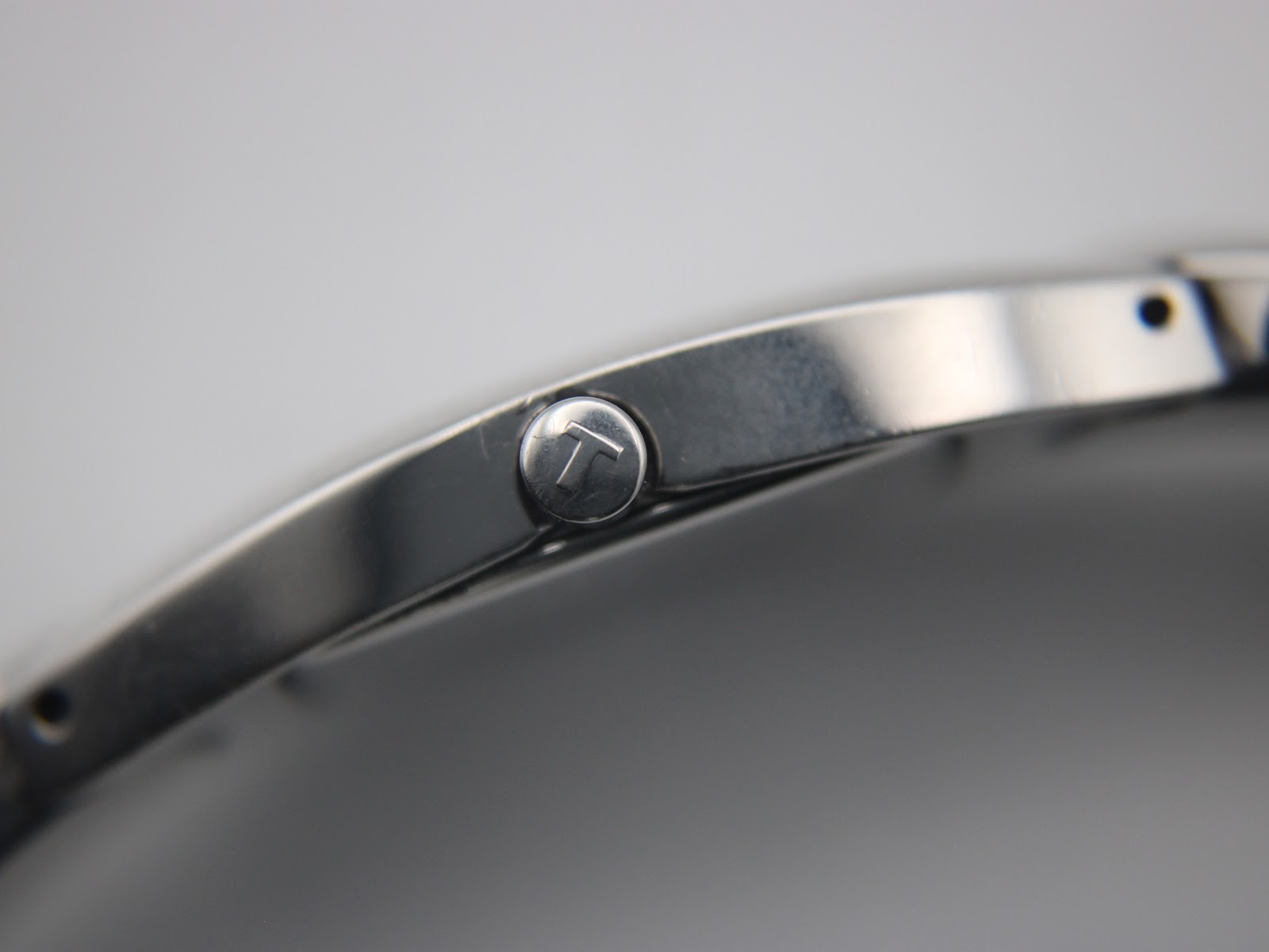 Close-up of the Tissot G345 watch crown, showing the Tissot 'T' logo.