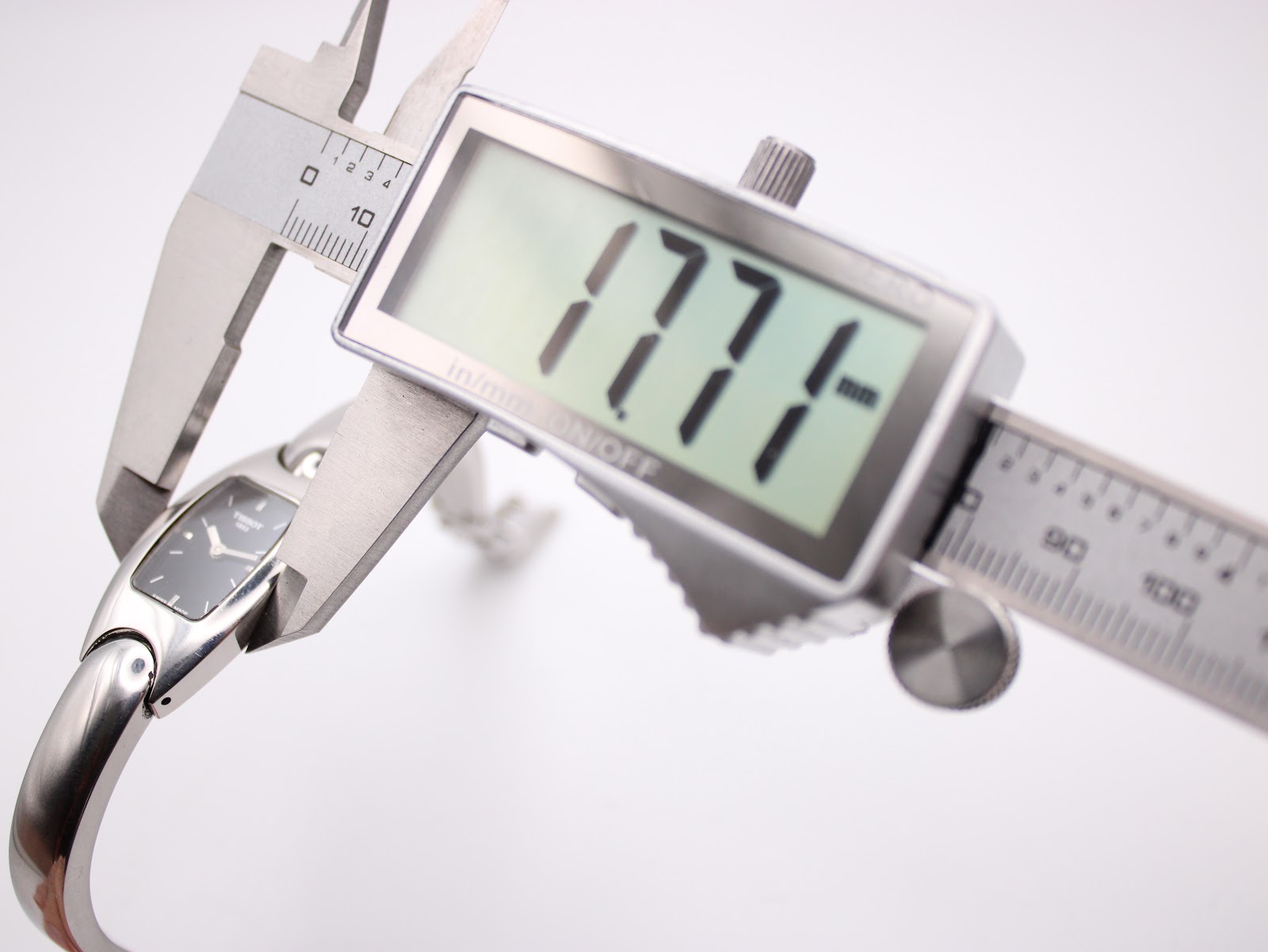Digital caliper measuring the Tissot G345 watch case diameter, showing a precise reading of 17.7mm.