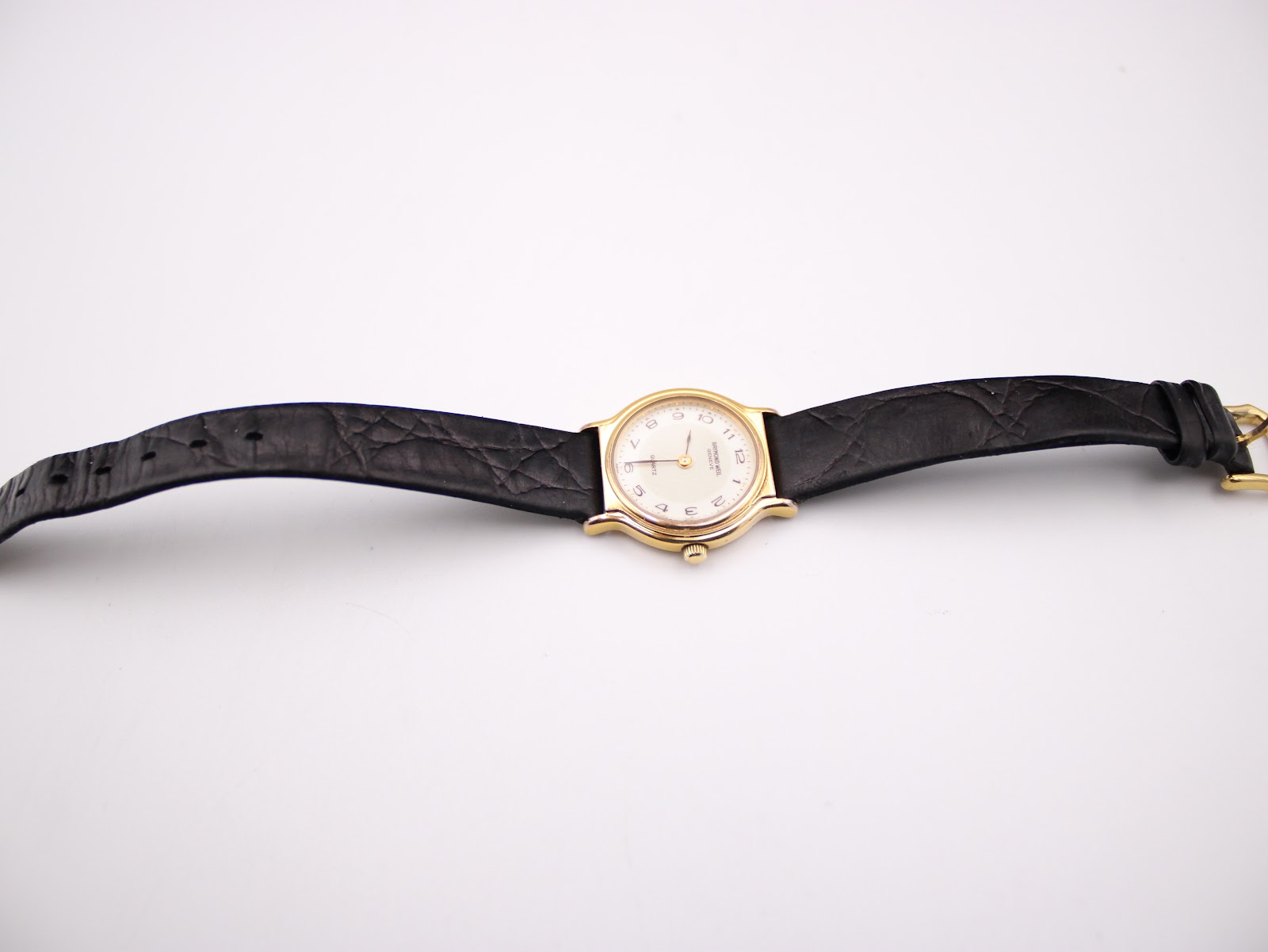 Top-down view of the Raymond Weil watch with black leather strap laid flat.