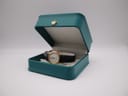 Raymond Weil watch displayed open in a teal presentation box.