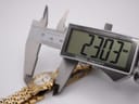 Digital caliper display showing a precise measurement of 23.03mm across the watch case, with the watch visible in the background.