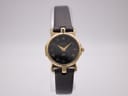 Front view of the Gucci 3400 L watch with gold-tone case, black dial, Roman numerals, and black textured leather strap.