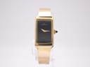Front view of Michel Herbelin 2267 gold tone rectangular watch with black dial on a clear stand.