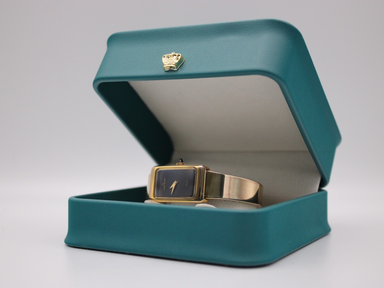 The Michel Herbelin watch displayed within an open teal presentation box.