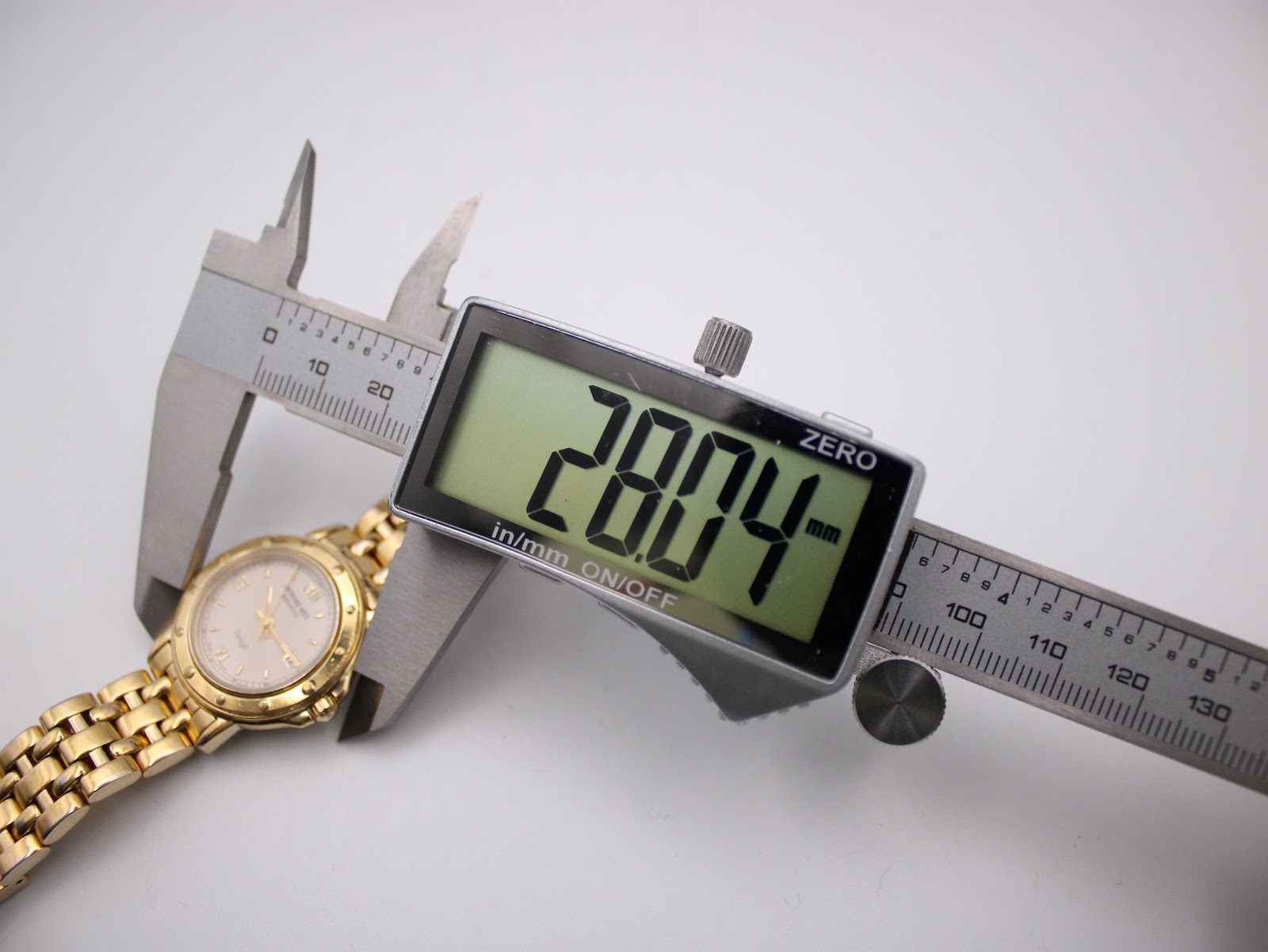 Digital caliper measuring the Raymond Weil Tango case, displaying a precise diameter of 28.04 mm.
