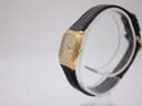 Angled side view of the Raymond Weil 5744 watch, highlighting the gold case and crown on a white display stand.
