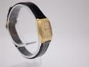 Another angled side view of the Raymond Weil 5744 watch, showcasing the profile of the rectangular gold case and black leather strap.
