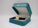 The Raymond Weil 5744 watch sitting inside a teal coloured generic display box with a cream interior.
