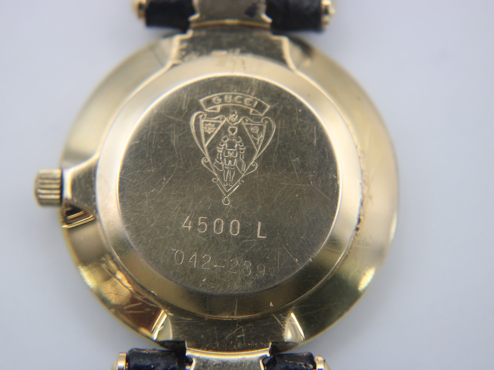 Close-up of the gold-plated case back of the Gucci 4500 L, showing model number and serial with surface scratches.