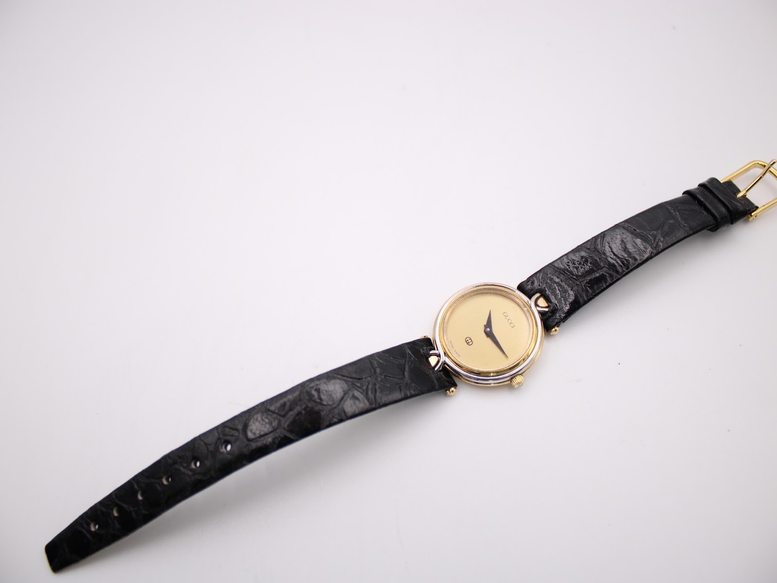 Overhead view of the Gucci 4500 L watch with its black leather strap laid flat, displaying the gold-tone buckle.