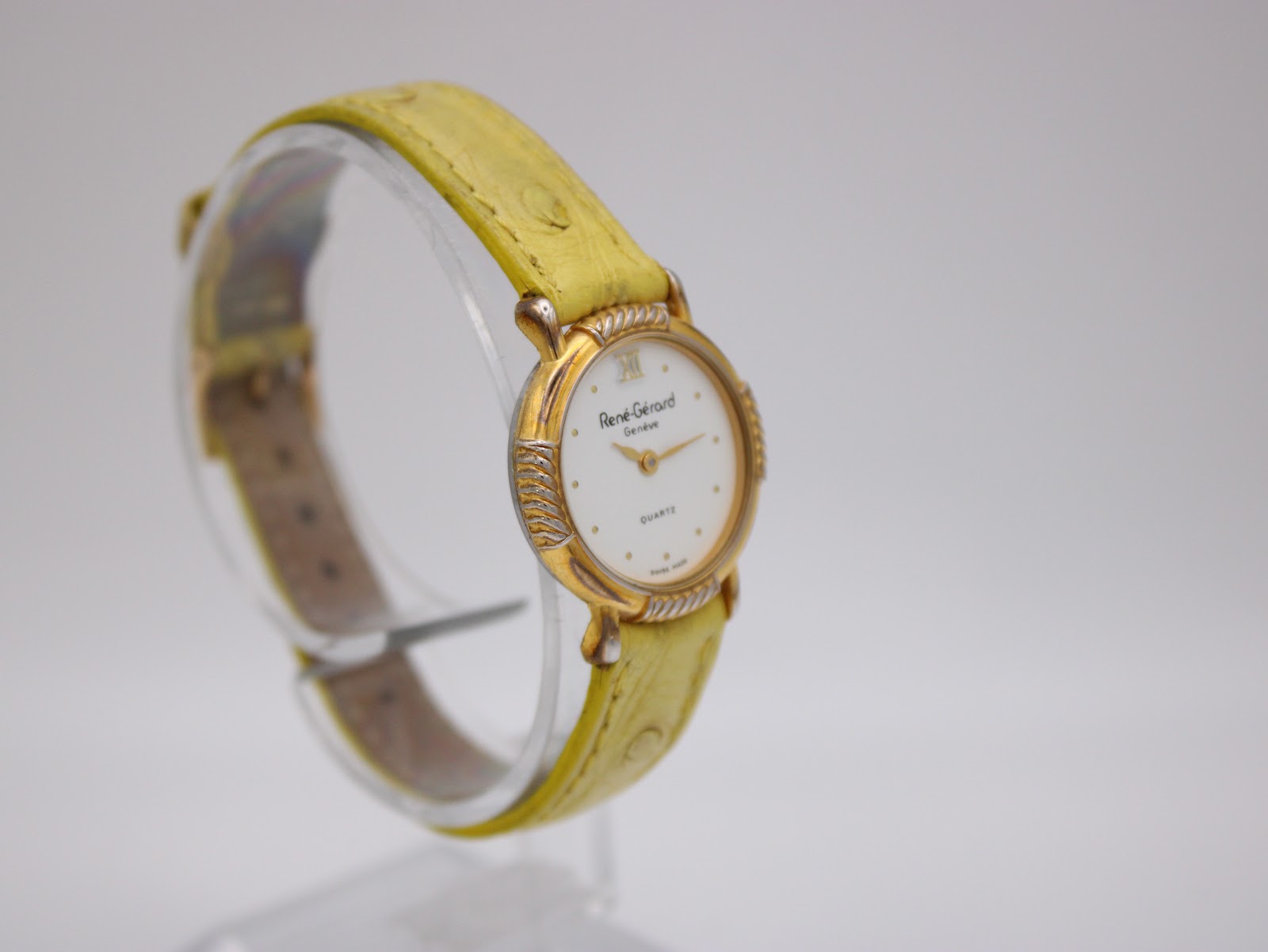 Another angled view of the René Gérard watch, showcasing the ornate gold-toned lugs and the texture of the yellow leather strap.