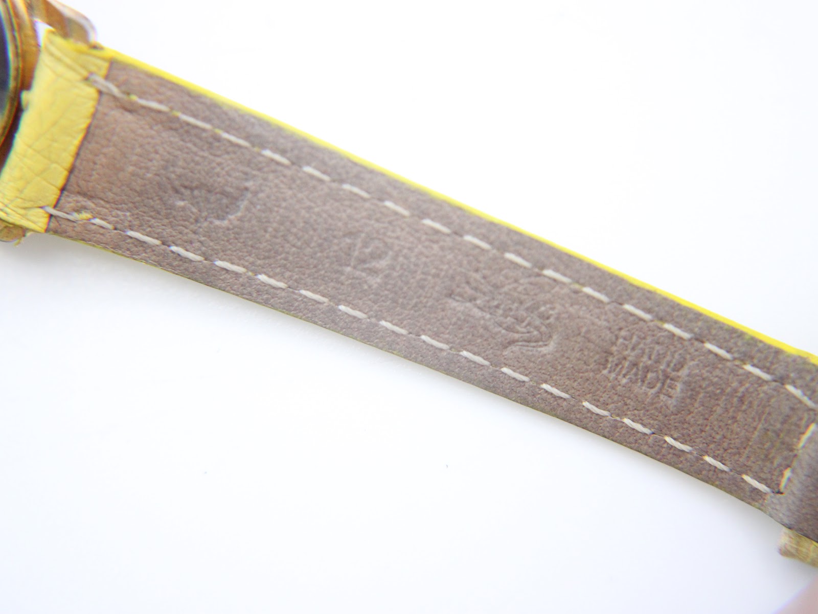 Close-up of the inner lining of the yellow leather strap, showing "HAND MADE" embossed text and stitching details.