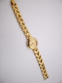 Overhead view of the entire Alfex gold watch and its woven bracelet laid flat.