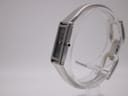 Side-angle view of the Gucci 1500 L watch, showing the crown and the curved stainless steel bangle bracelet.