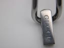 Extreme close-up of the integrated stainless steel bracelet's clasp, clearly showing the engraved "GUCCI" logo.