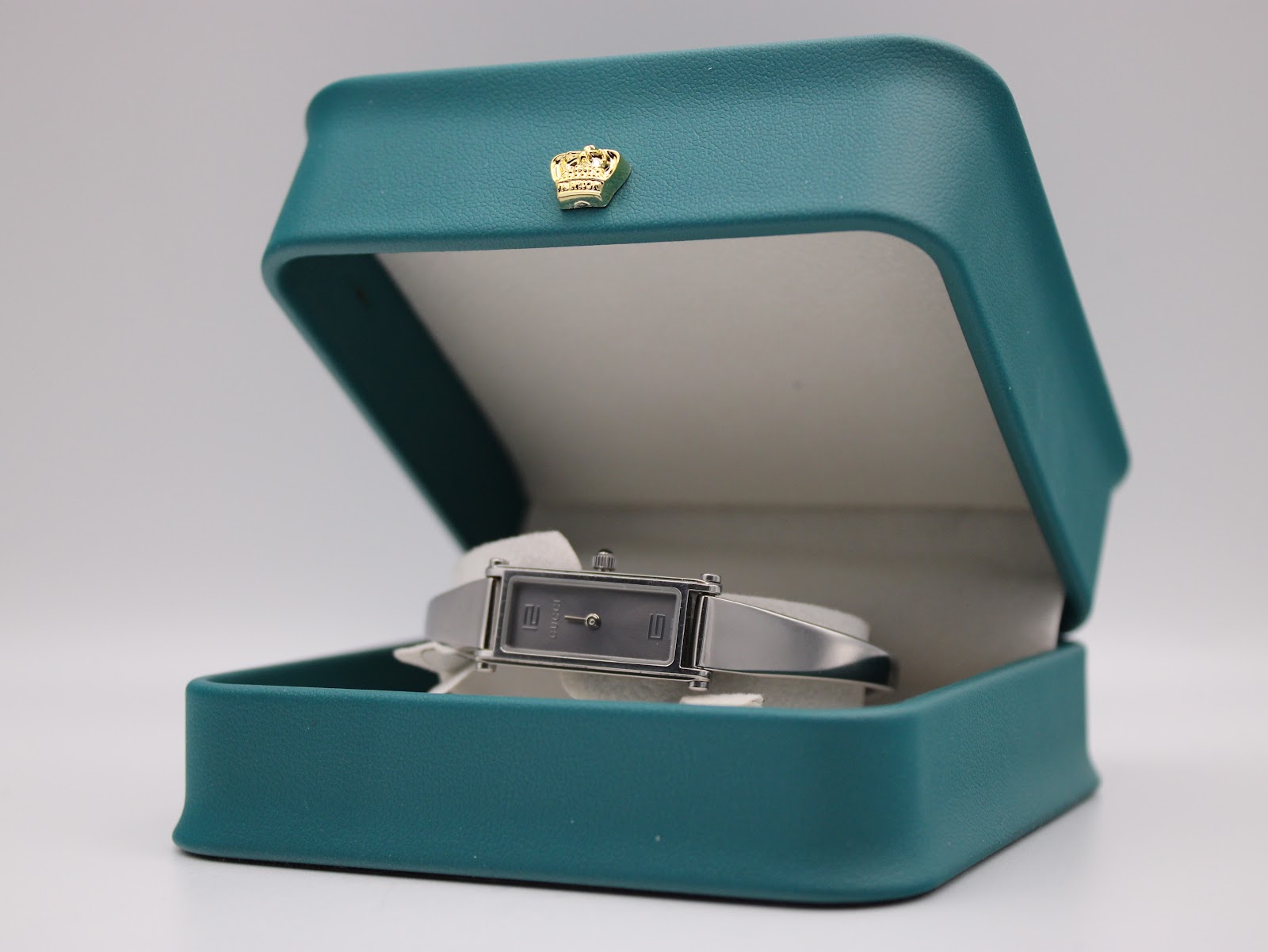 The Gucci 1500 L watch resting inside an open green presentation box with a gold crown emblem.