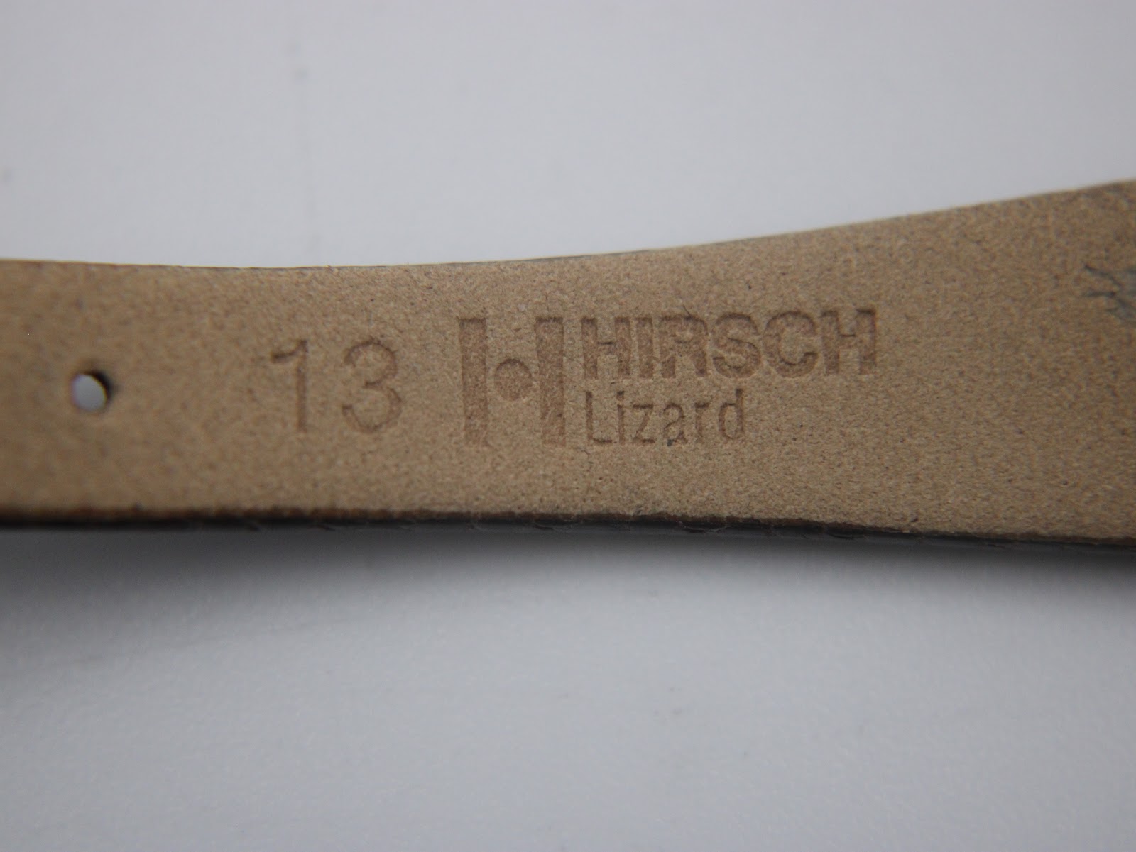 Close-up of the underside of the watch strap, showing the embossed '13 HIRSCH Lizard' marking, indicating lug width and material.