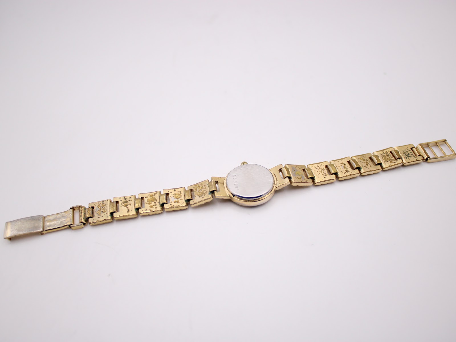 Back view of the Bulova watch, showing the plain stainless steel case back and the gold-tone bracelet with some wear on the underside.