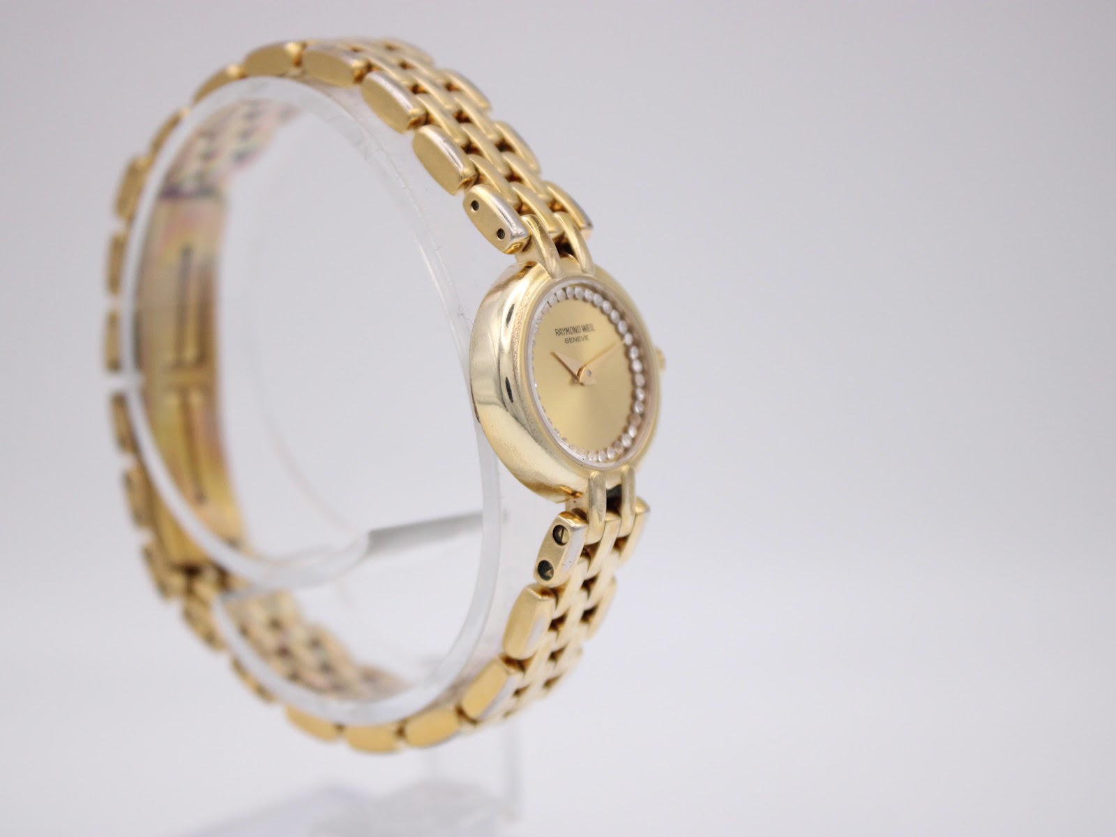 Another angled side view of the watch on its display, showing the watch face and the integrated bracelet design.