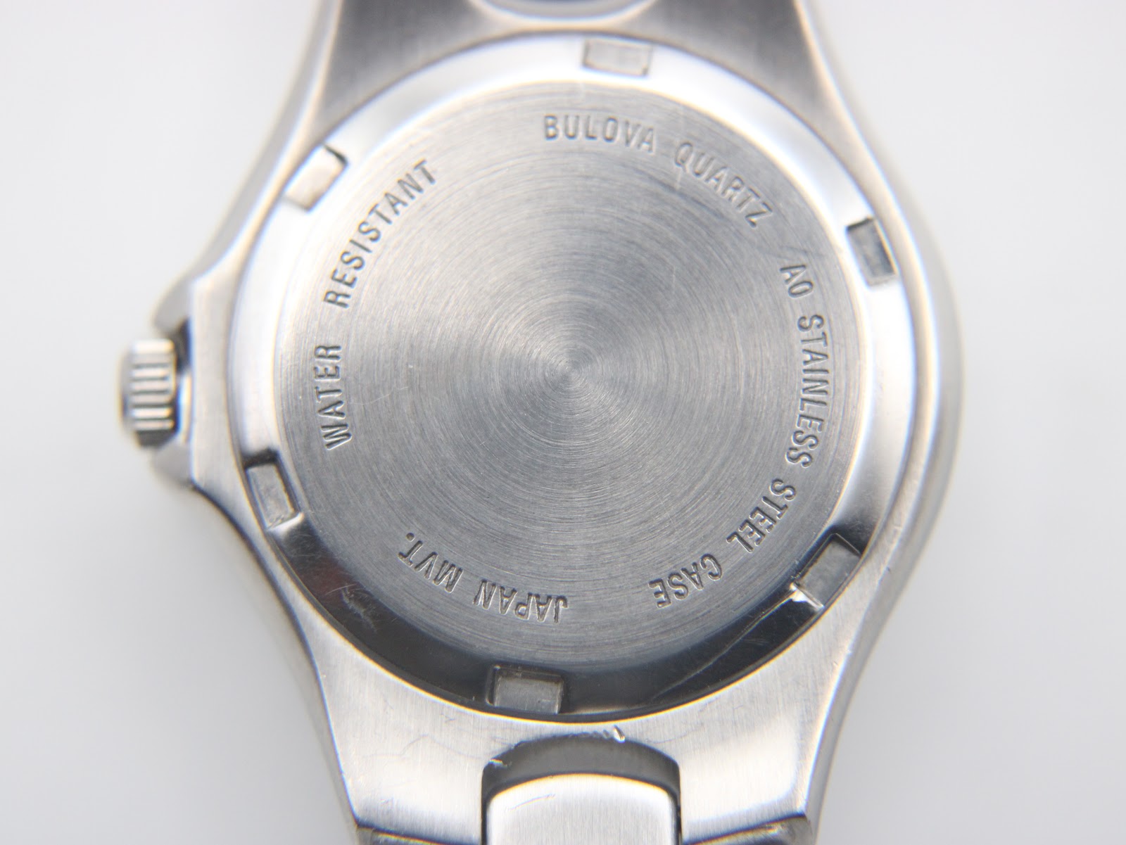 Close-up of the brushed stainless steel case back, with engravings including "Bulova Quartz", "Water Resistant", "Japan Mvt.", "AO Stainless Steel Case".