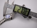 Digital caliper measuring the case diameter of the Bulova Marine Star watch, displaying 27.08 mm on screen.