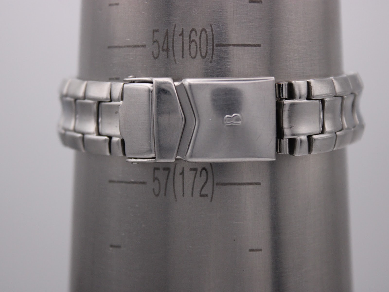 The watch bracelet clasped around a metal wrist sizing gauge, showing a wrist circumference reading of approximately 16.0cm (54mm diameter).
