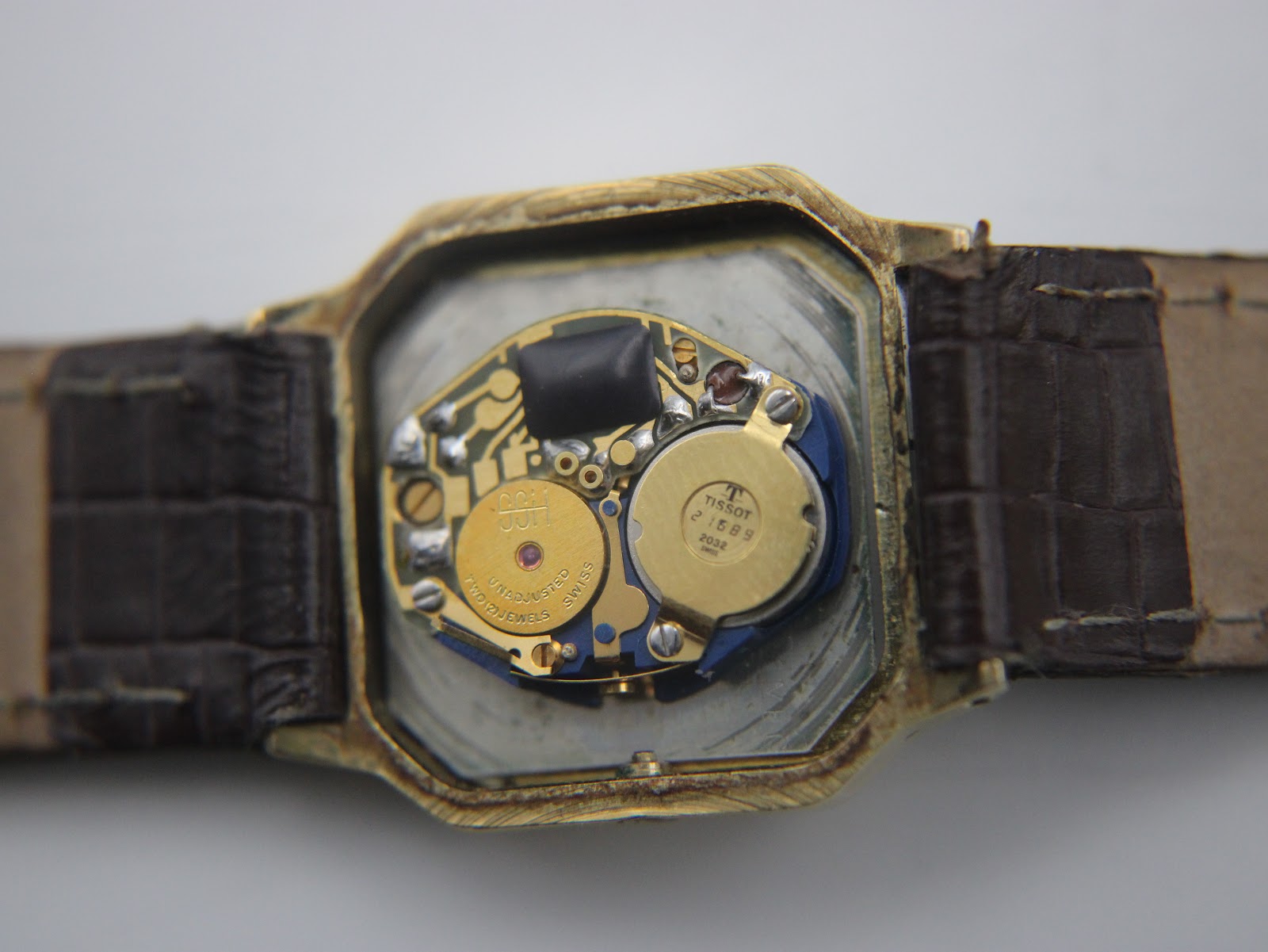 Close-up of the Tissot 21589 quartz movement with 'TISSOT 21589' and '7 jewels unadjusted' visible on internal components.