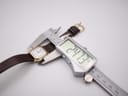 Digital caliper measuring the Tissot 21589 watch case, showing a precise width of 24.73mm.
