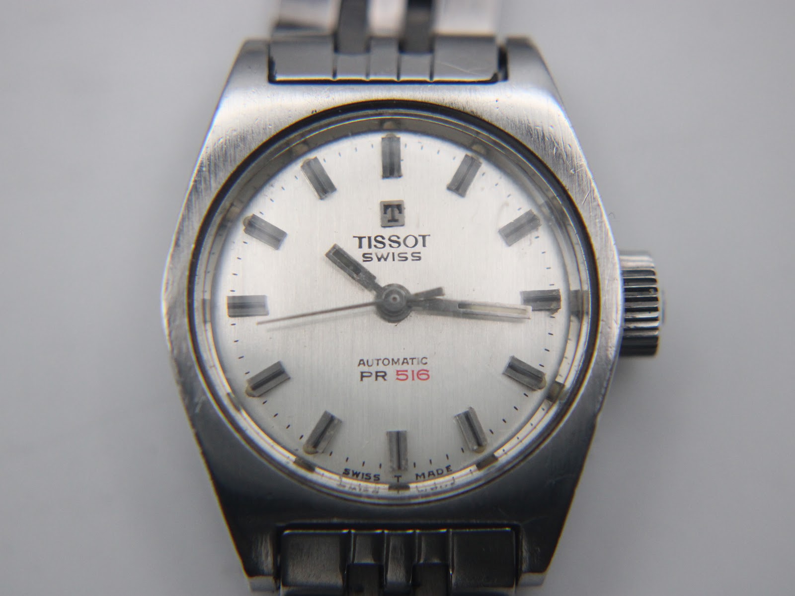 Close-up of the silver dial of the Tissot PR 516, showing applied baton indices, hands, and 'AUTOMATIC PR 516' text.
