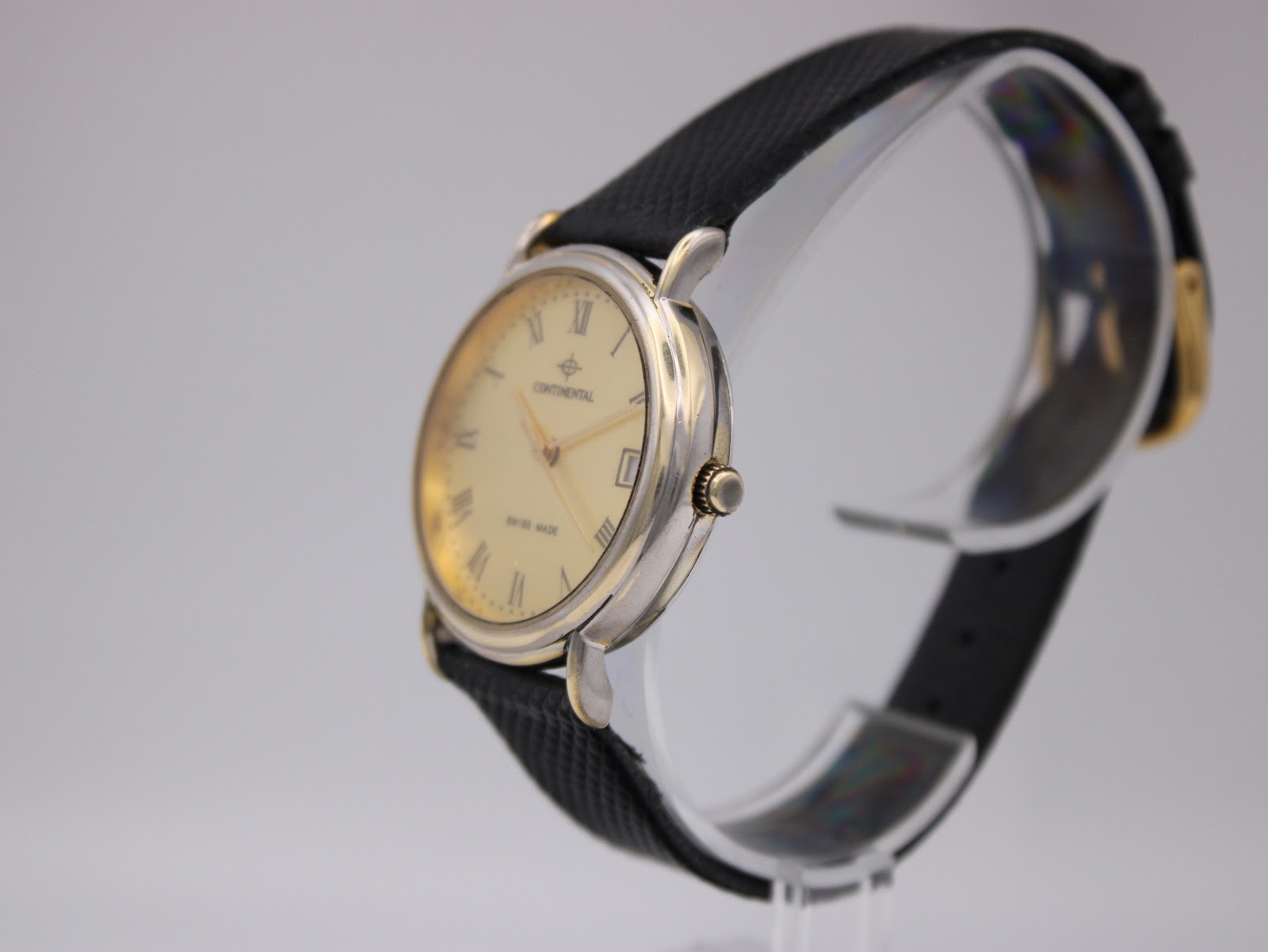 Side profile view of the Continental watch on a transparent display stand, showing the two-tone case and crown details.