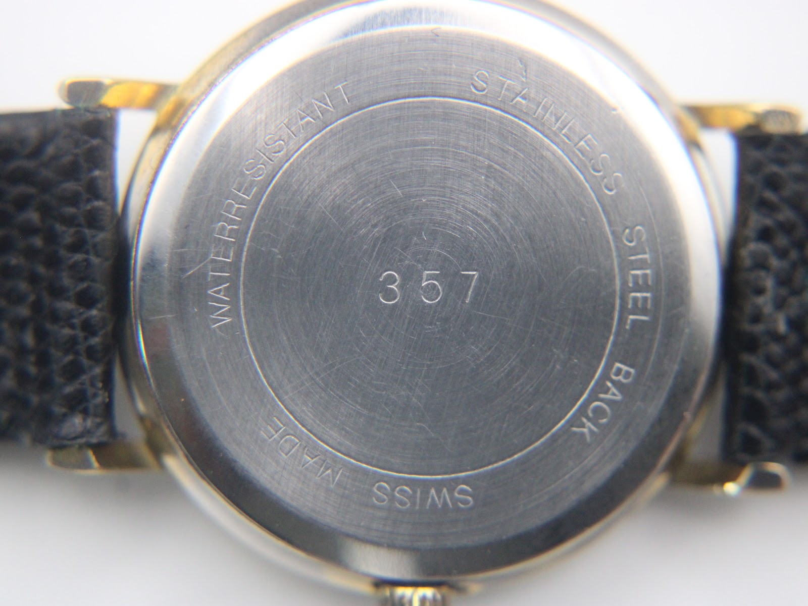 Close-up of the watch's brushed stainless steel case back, clearly engraved with 'WATERRESISTANT', 'STAINLESS STEEL BACK', 'SWISS MADE', and the model number '357'.