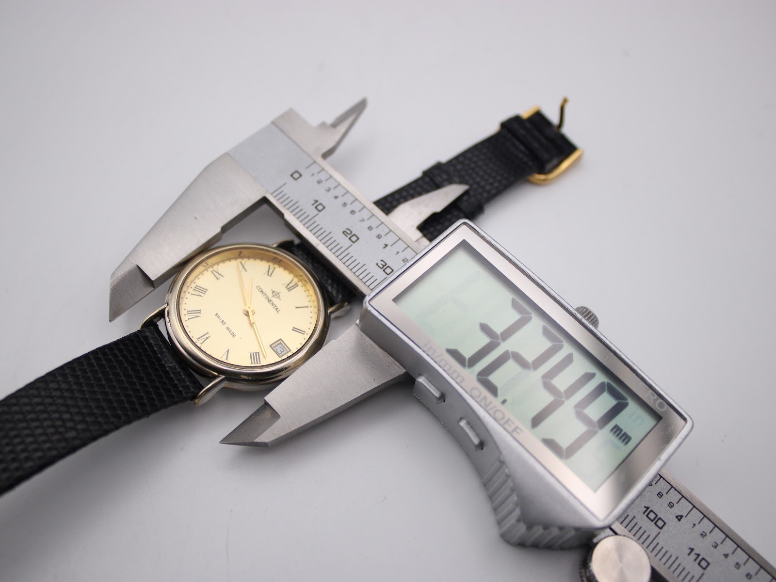 Overhead shot of the Continental watch case being measured by a digital caliper, displaying a precise diameter of 32.49mm.