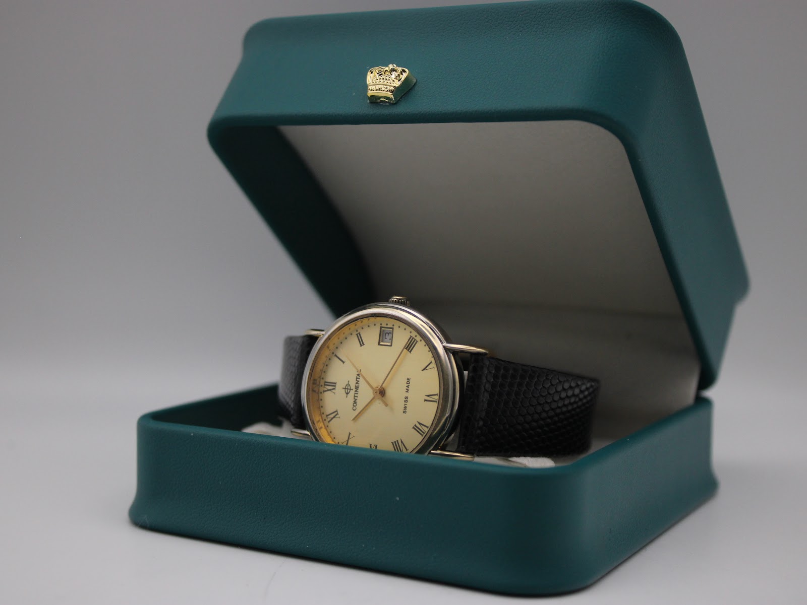 The Continental watch with its black leather strap, displayed neatly inside a green presentation box with a gold crown emblem.