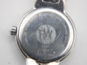 Close-up of the Raymond Weil watch case back, showing 'STAINLESS STEEL WATER RESISTANT 3ATM SAPPHIRE CRYSTAL' and '5830 Z364677 SWISS MADE' engravings, with surface scratches.