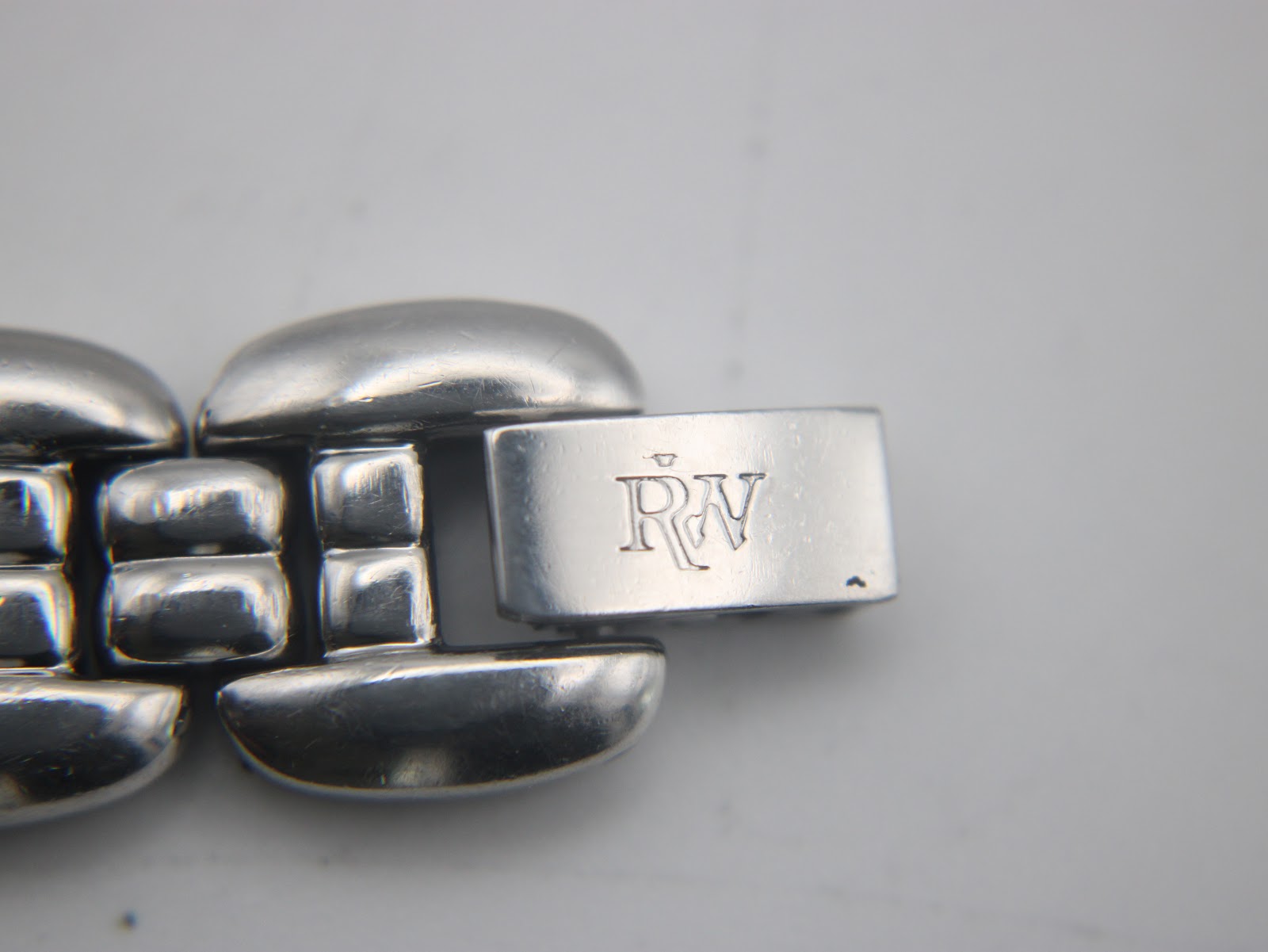 Close-up of the Raymond Weil watch's stainless steel fold-over clasp, clearly showing the engraved 'RW' logo.