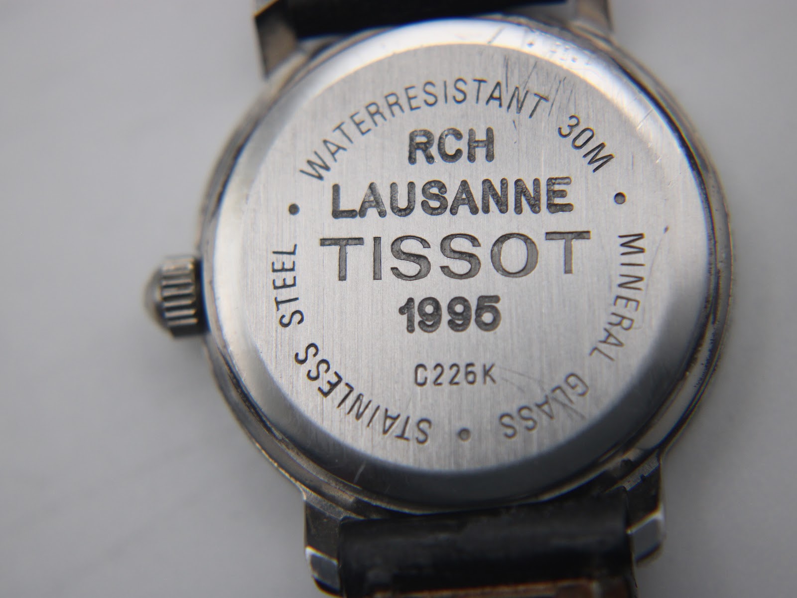 Close-up of the stainless steel case back of the Tissot C226K, showing engravings 'WATERRESISTANT 30M', 'LAUSANNE', 'TISSOT 1995', 'C226K', 'STAINLESS STEEL', and 'MINERAL GLASS'.