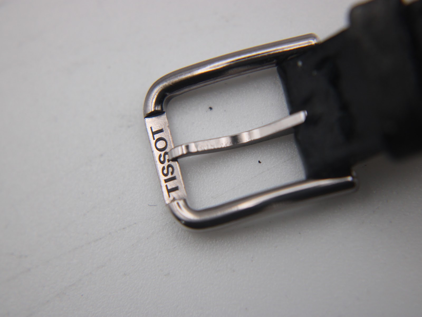 Detailed shot of the polished stainless steel buckle, clearly engraved with 'TISSOT'.