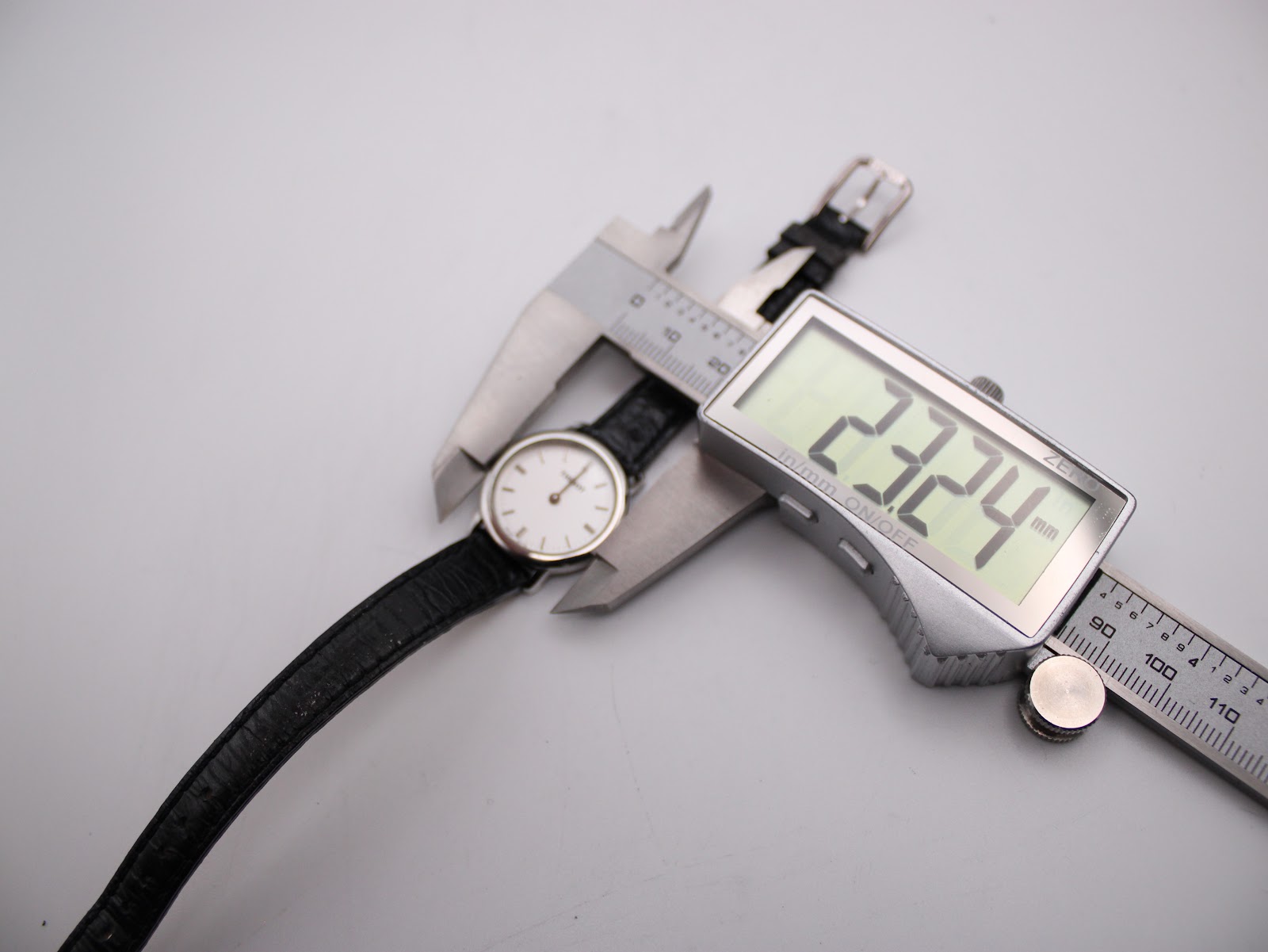 Overhead shot of the Tissot C226K watch being measured by a digital caliper, displaying a case diameter of 23.24mm.
