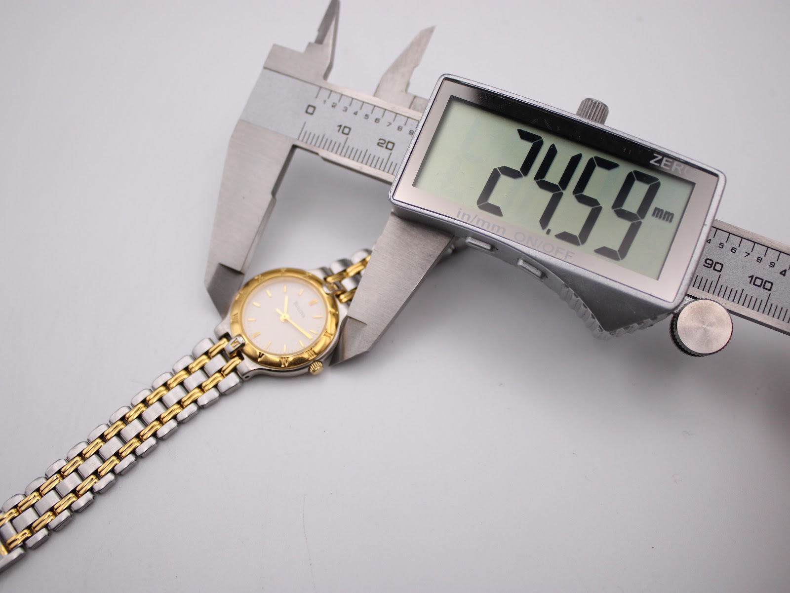 Digital caliper measuring the watch case, displaying a precise diameter of 24.59 mm.