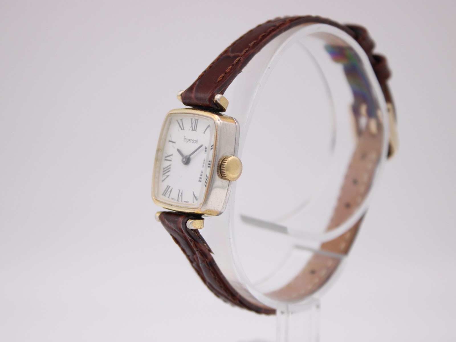 Angled side view of the vintage Ingersoll watch, showing the rectangular two-tone case and gold-tone crown.