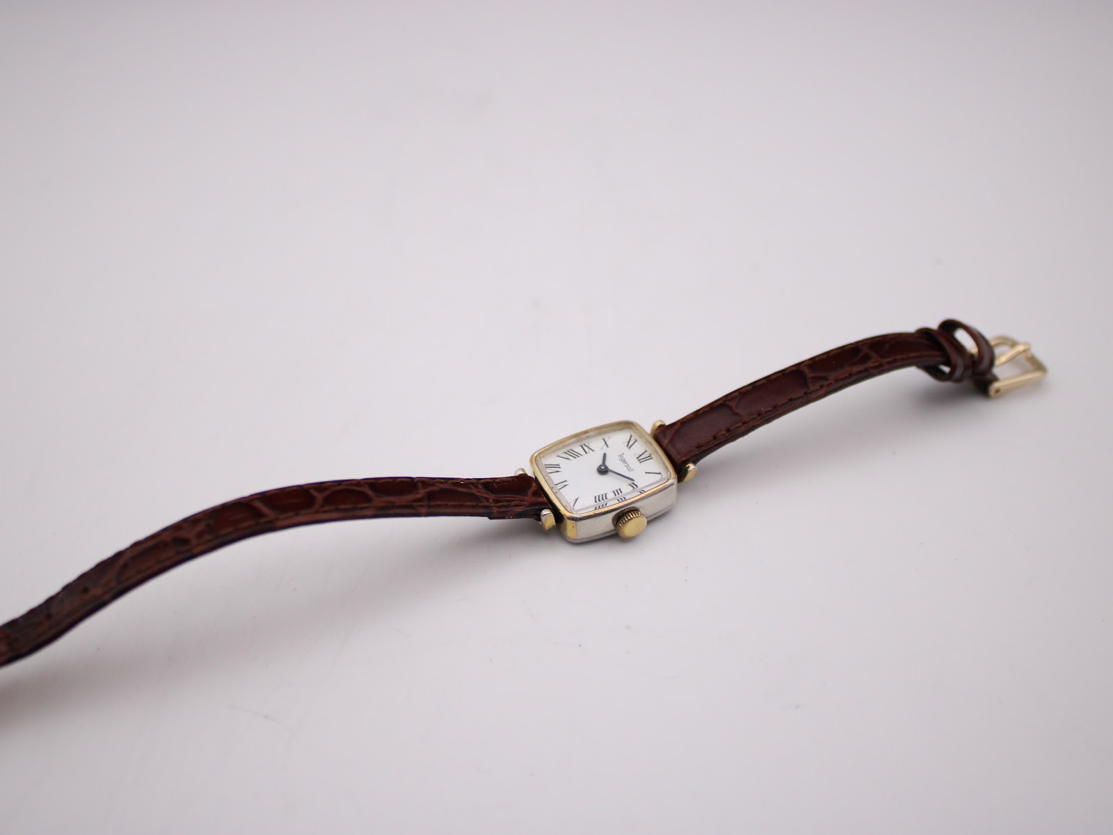 Top-down view of the Ingersoll watch with its brown crocodile-effect leather strap extended on a white background.