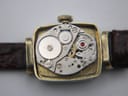 Close-up view of the manual wind Swiss movement, showing gears and 'one jewel' inscription inside the watch case.