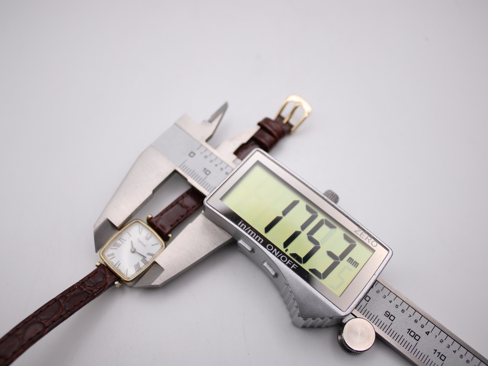 Digital caliper measuring the watch case width, displaying a precise measurement of 17.53mm.