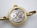 Close-up of the manual wind movement inside the watch case, showing gears and "17 seventeen jewels" engraving.