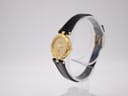 Angled view of the gold Westar watch with champagne dial and black leather strap on a display stand.