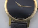 Close-up of the black Movado Museum Dial, showing the iconic gold dot at 12 o'clock, gold hands, and "Swiss Movado Quartz" text.