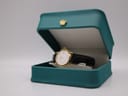 The Raymond Weil 9972 watch displayed in an open teal coloured presentation box with a gold crown emblem on the lid.