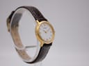 Another angled side view of the Tissot C225K watch on a stand, showing the brown leather strap and gold-tone buckle.