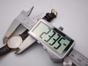 Digital caliper measuring the Tissot watch case, displaying a precise diameter of 23.35mm.